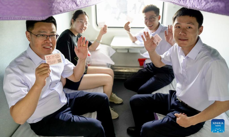 Passengers aboard the first train of the Hotan-Ruoqiang Railway show their train tickets in northwest China's Xinjiang Uygur Autonomous Region, June 16, 2022.