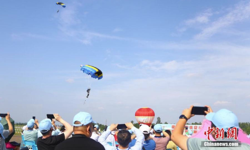 People watch parachuting performance during the 2022 Jiangxi Aviation Sports Tourism Festival in Ji'an, east China's Jiangxi Province, June 14, 2022. (Photo: China News Service/Liu Zhankun)