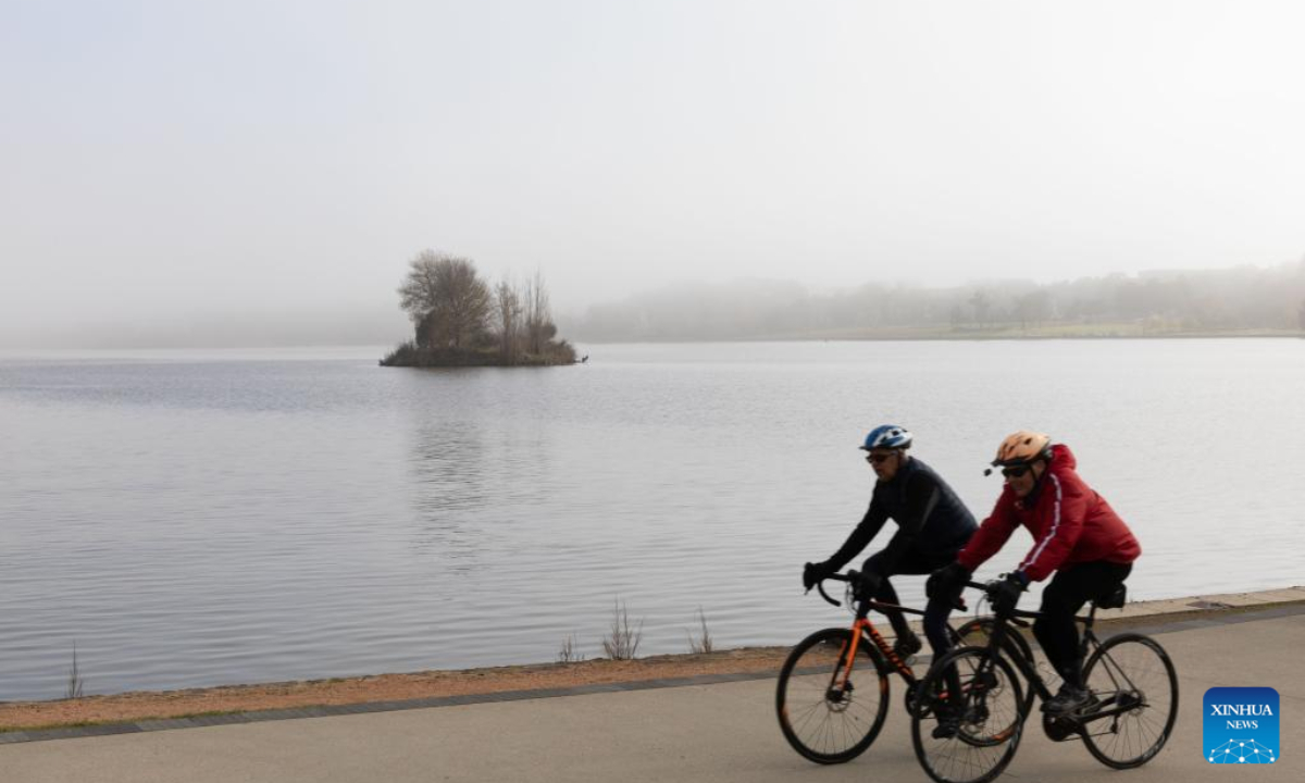 People ride bikes along the Lake Burley Griffin in the thick fog in Canberra, Australia on June 17, 2022. Photo:Xinhua