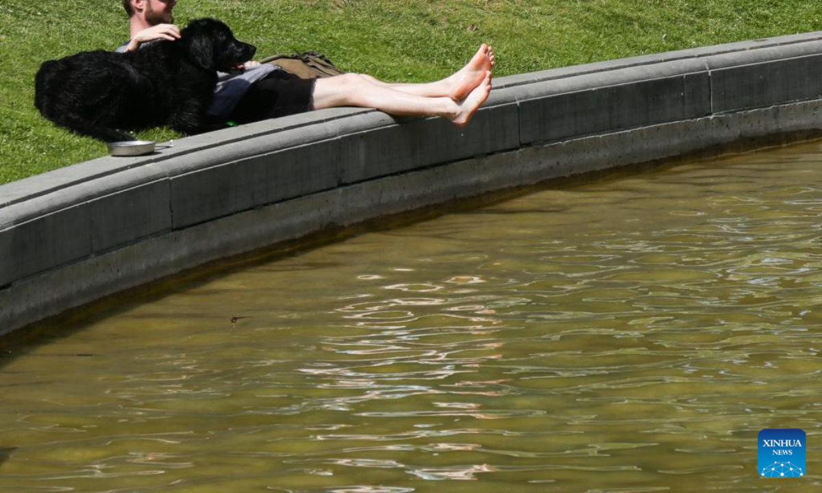 A man and his dog rest near a pond at the Park of the Fiftieth Anniversary in Brussels, Belgium, June 17, 2022. Belgium witnesses a heat wave with temperature expected to reach 34 degrees centigrade in Brussels in the following days. Photo:Xinhua