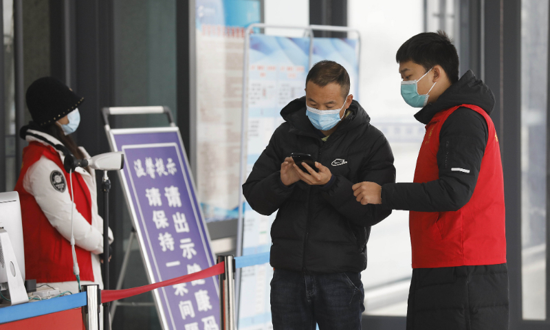 An anti-epidemic volunteer checks the health code of a passenger at Pingdingshan West high-speed railway station in Henan Province on January 11, 2022. Photo: VCG