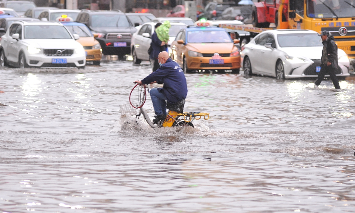 A resident rides an electric bike on a flooded road in Harbin, capital of Northeast China's Heilongjiang Province on June 16, 2022. A sudden storm hit Harbin on the day, prompting the city's meteorological authorities to issue a yellow rainstorm alert. Photo: VCG