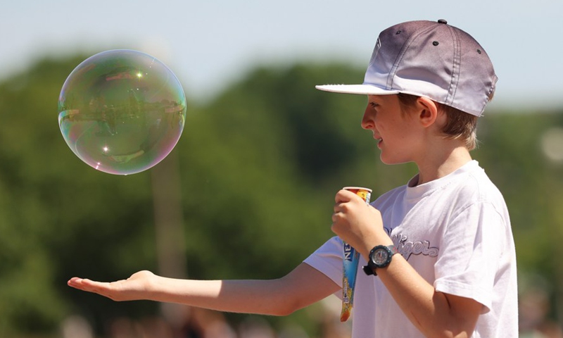 A boy has a popsicle as he chases a soap bubble near the Eiffel Tower in Paris, France, on June 16, 2022.Photo:Xinhua