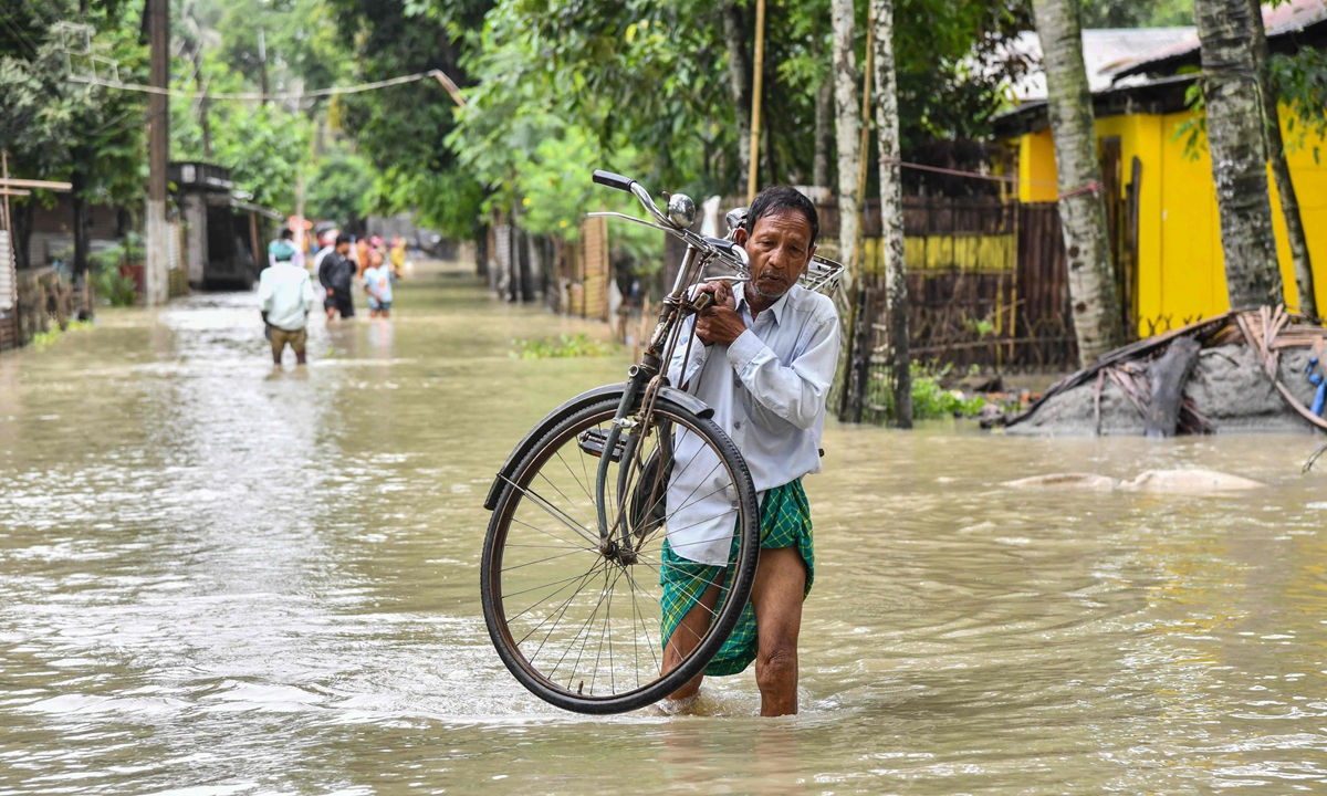 A man carries his bicycle as he wades through floodwaters in Solmara of Nalbari district, in India's Assam State on June 19, 2022. Photo: VCG