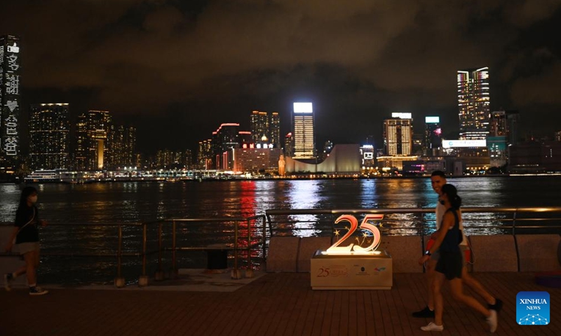 People walk past a celebratory decoration illuminated for the 25th anniversary of Hong Kong's return to the motherland in Hong Kong, south China, June 18, 2022.Photo:Xinhua
