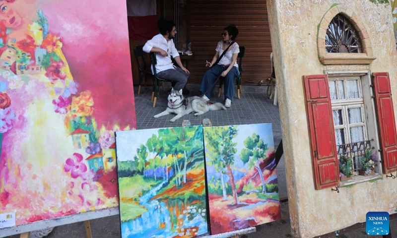 People sit and chat behind an art booth during a street festival held in Mar Mikhael, in Beirut, Lebanon, June 19, 2022.(Photo: Xinhua)