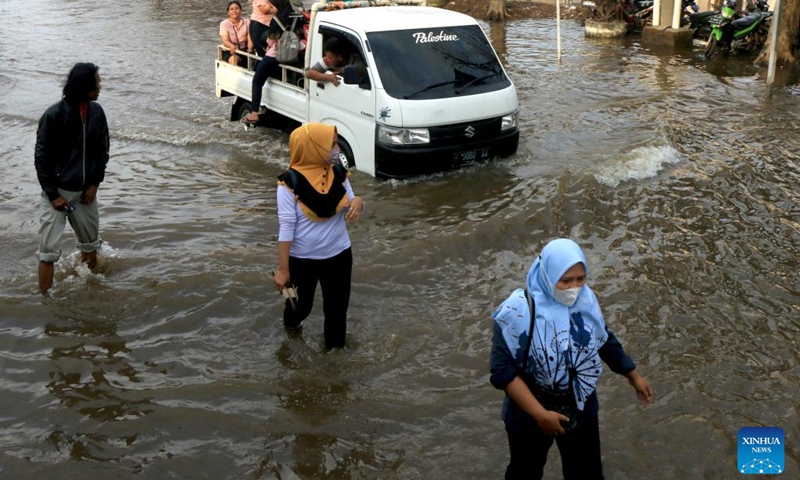 People wade through flood water after high tides at Tanjung Emas Port on the coast of Semarang, Central Java, Indonesia, June 21, 2022.(Photo: Xinhua)