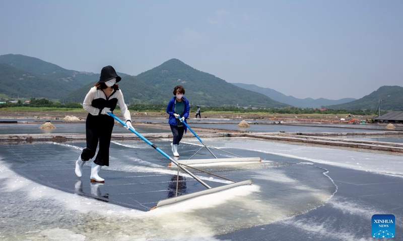 People shove salt crystals in a sea salt making pond in Buan County, North Jeolla province, South Korea, June 21, 2022. Located in coastal area, the chequered salt ponds here maintain the traditional practice of producing salt.(Photo: Xinhua)