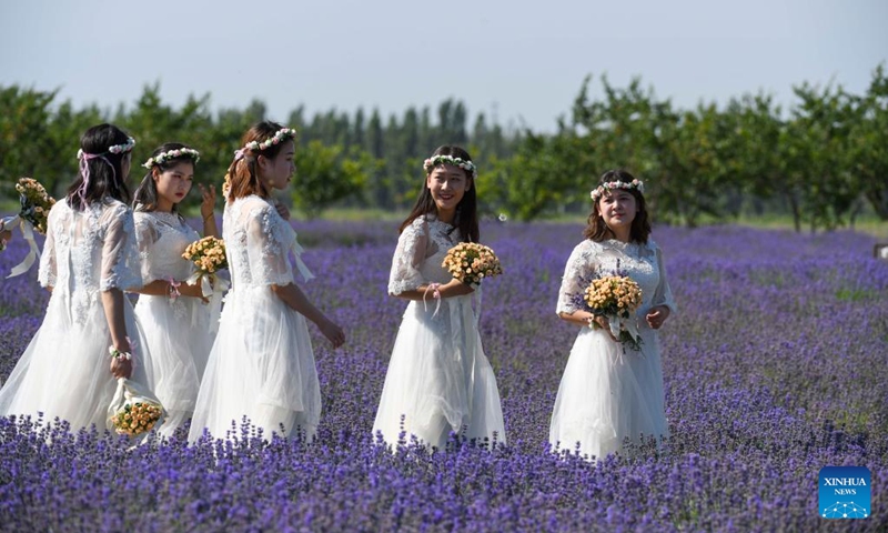 Image ambassadors walk in lavender fields in Sigong Village, Huocheng County of northwest China's Xinjiang Uygur Autonomous Region, June 22, 2022. Sigong Village has planted 12,000 mu (about 800 hectares) of lavender. The lavender planting bases here have promoted local tourism and lavendar processing industry. In 2021, per capita income in Silong Village reached 25,000 yuan (3,735 US dollars). (Xinhua/Zhao Ge)