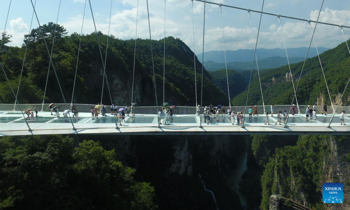 Aerial photo shows tourists walking on a glass-bottomed bridge at Zhangjiajie Grand Canyon, central China's Hunan Province, July 8, 2022. As the summer vacation approaches, Zhangjiajie, a popular tourist destination in Hunan Province, has taken a series of measures to boost the recovery of tourism. Photo:Xinhua