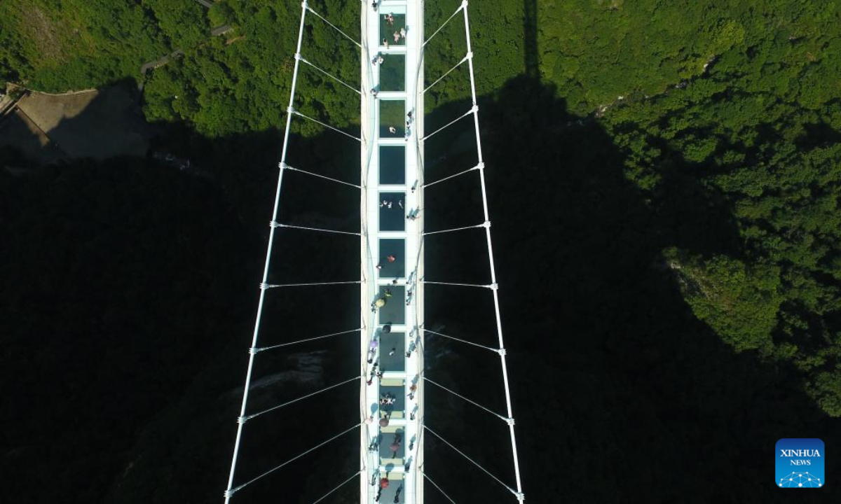 Aerial photo shows tourists walking on a glass-bottomed bridge at Zhangjiajie Grand Canyon, central China's Hunan Province, July 8, 2022. As the summer vacation approaches, Zhangjiajie, a popular tourist destination in Hunan Province, has taken a series of measures to boost the recovery of tourism. Photo:Xinhua