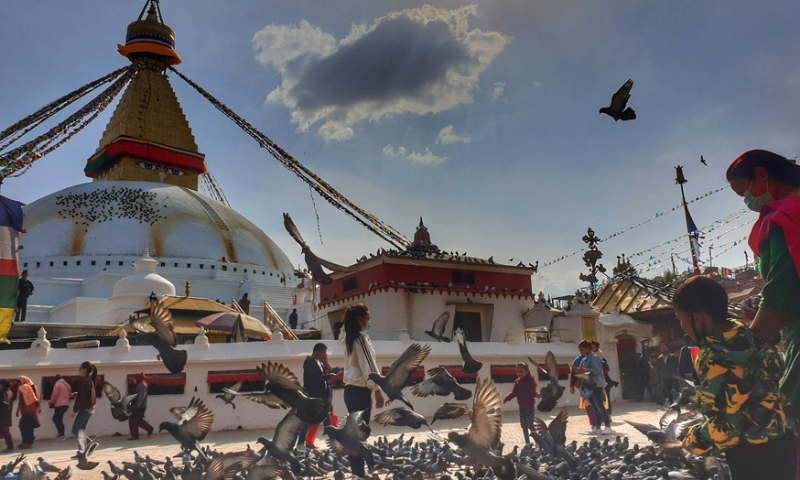 People feed pigeons around Boudhanath Stupa, the world heritage site in Kathmandu, capital of Nepal, March 18, 2020. Photo: Xinhua