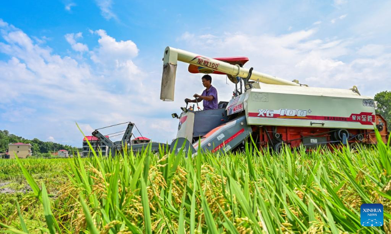 A harvester works in a rice field in Huaqiao Village of Shuangfeng County, central China's Hunan Province, July 6, 2022. (Photo by Li Jianxin/Xinhua)