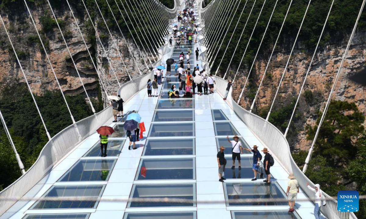 Tourists walk on a glass-bottomed bridge at Zhangjiajie Grand Canyon, central China's Hunan Province, July 8, 2022. As the summer vacation approaches, Zhangjiajie, a popular tourist destination in Hunan Province, has taken a series of measures to boost the recovery of tourism. Photo:Xinhua