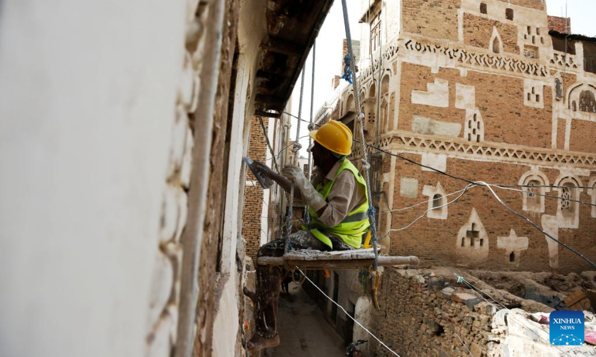 A worker renovates the facade of a house in Old Sanaa City, Yemen, on July 5, 2022. The old city of Sanaa was inscribed on the World Heritage List of the UNESCO in 1986. The old city has been inhabited for more than 2,500 years. The 6,000 mud-brick tower houses are decorated with geometric patterns of white plaster and stained glass windows. Photo:Xinhua