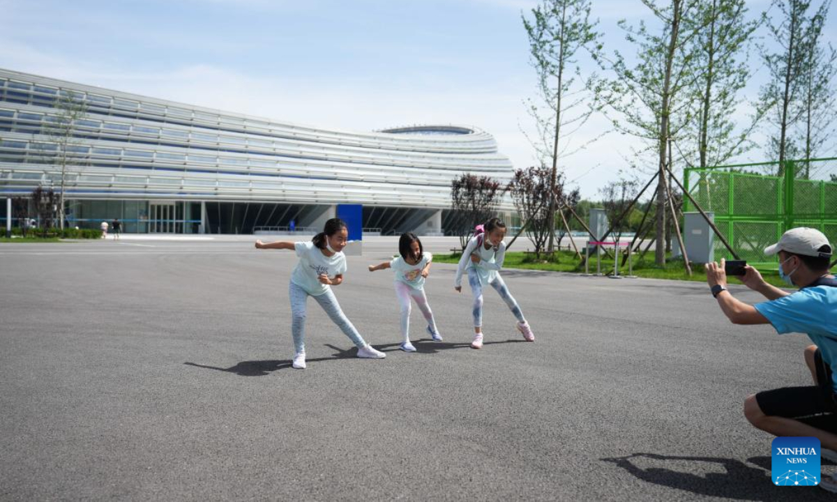 Tourists pose for photos outside the National Speed Skating Oval in Beijing, capital of China, July 9, 2022. The National Speed Skating Oval, also known as the Ice Ribbon, opened to the public on Saturday. Photo:Xinhua