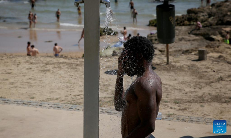 A man takes a shower at the Carcavelos beach in Cascais, Portugal, July 9, 2022. (Photo by Pedro Fiuza/Xinhua)