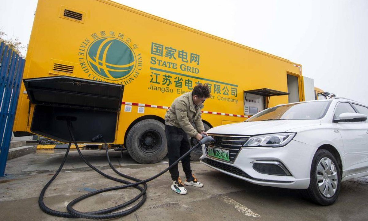 A staffer charges an electric vehicle (EV) using a mobile charging pile at the Guangling service area on the Beijing-Shanghai Expressway in Taizhou, East China's Jiangsu Province, on January 26, 2022. The mobile charging pile - a special vehicle - has four 30-kilowatt charging piles, which can serve four EVs simultaneously. It takes one hour to recharge an EV. Photo: cnsphoto