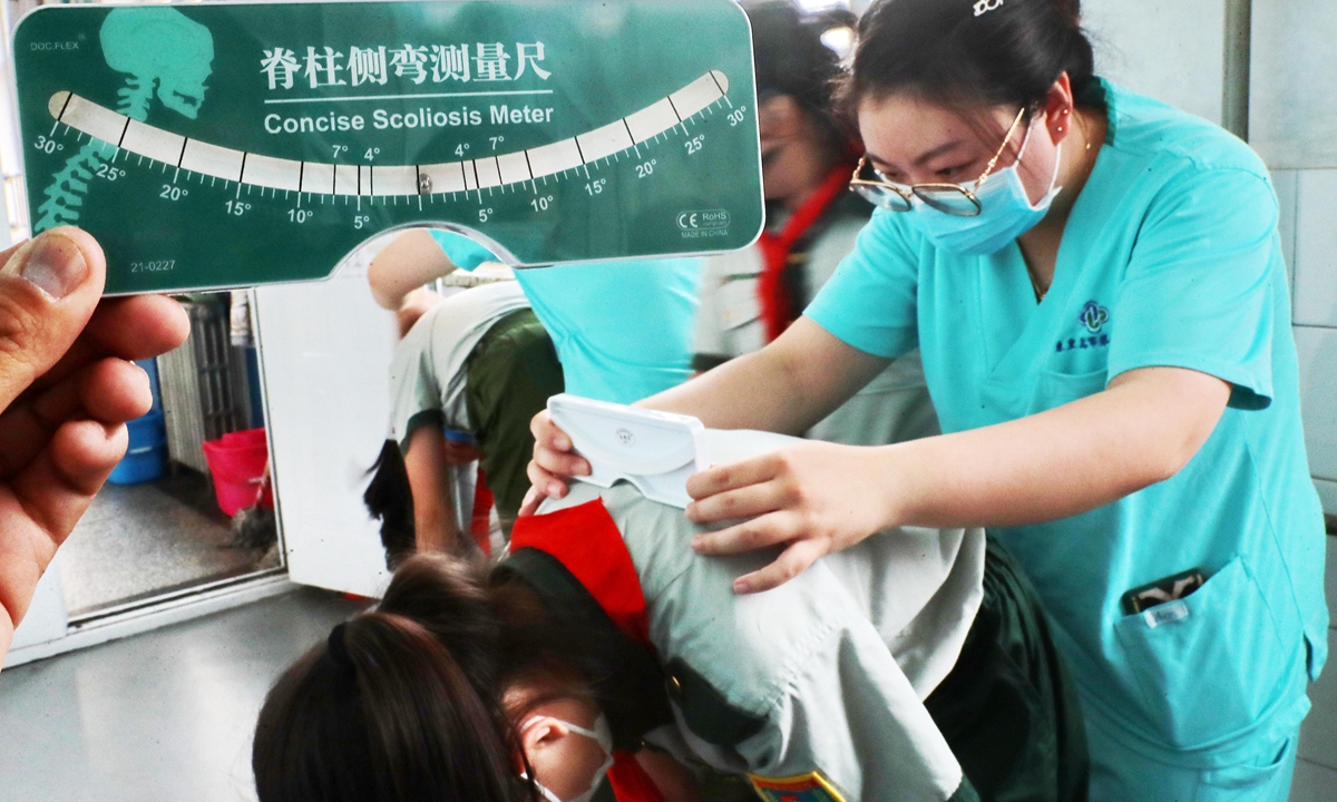 Medical workers from First Hospital of Qinhuangdao in North China's Hebei Province conduct spinal examinations on grade four students from a local school to prevent spinal deformity in the early stages. Photo: IC