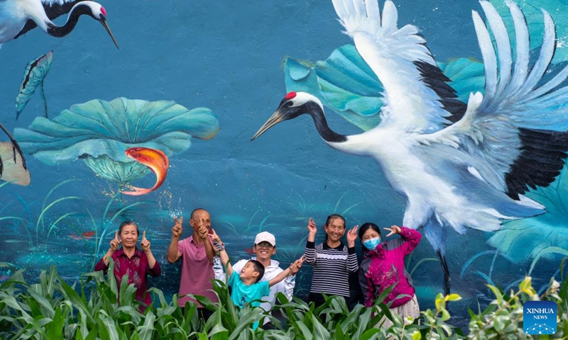 Liu Zhicheng (C) poses for a photo with villagers after finishing a wall painting in Yongsheng County, Lijiang City, southwest China's Yunnan Province, June 24, 2022.Photo:Xinhua
