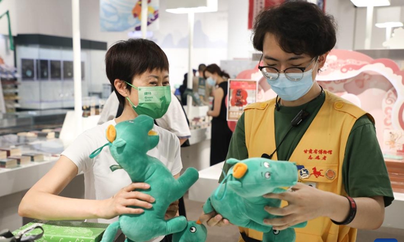 A tourist (L) selects souvenirs featuring an ancient bronze horse statue at a store in Gansu Provincial Museum in Lanzhou, capital of northwest China's Gansu Province, June 28, 2022. The bronze horse statue, popularly known as Bronze Galloping Horse Treading on a Flying Swallow, was unearthed in 1960s from the Leitai Tomb of the Eastern Han Dynasty (25-220 AD) in Wuwei and is now preserved in the Gansu Provincial Museum.(Photo: Xinhua)