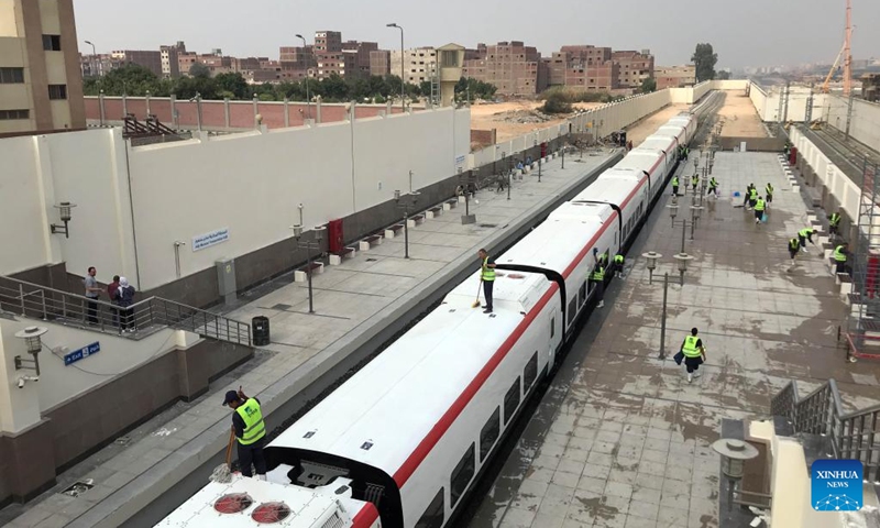 Workers clean the light rail train during a trial run at Adly Mansour station in Cairo, Egypt, June 30, 2022. Egypt is building its first light rail transit (LRT) system, which will be the first means of mass transport linking the new Administrative Capital to Greater Cairo when completed.  (Photo: Xinhua)