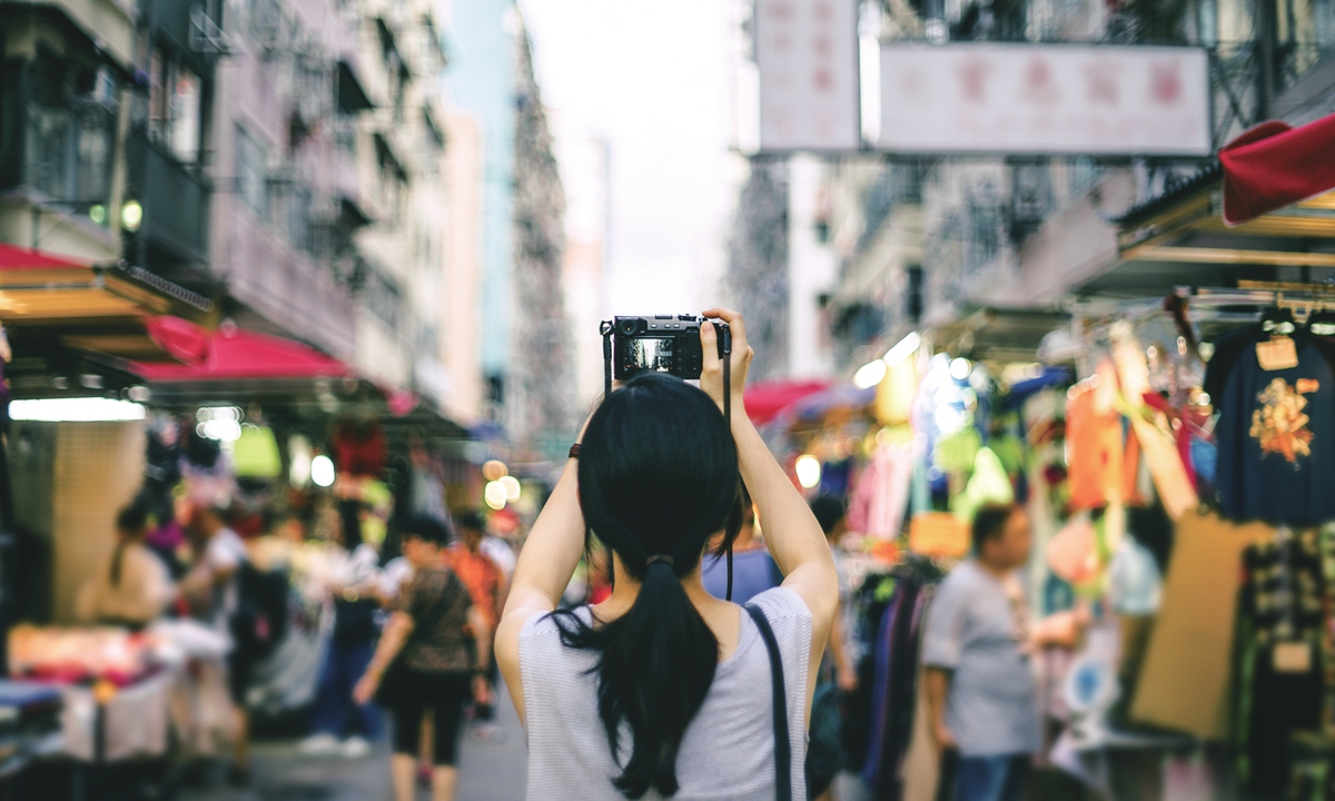 A young woman takes a photo of the street view in HKSAR. Photo: VCG