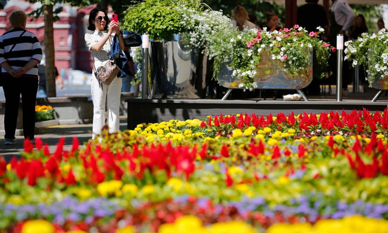 A woman takes pictures during an annual flower festival outside the GUM department store near Red Square in central Moscow, Russia, on July 1, 2022.(Photo: Xinhua)