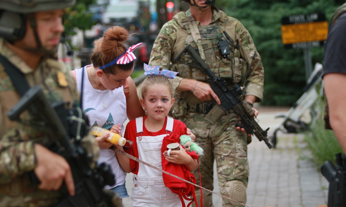 US law enforcers escort a family from the scene of a mass shooting at an Independence Day parade on July 4, 2022 in Highland Park, Illinois. Police have detained Robert 