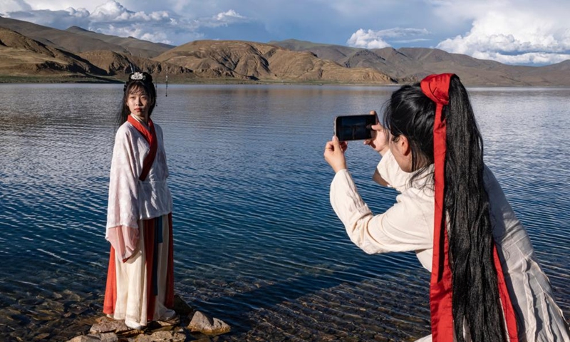 Visitors take pictures by the lakeside of Yamdrok Lake in Nagarze County of Shannan City, southwest China's Xizang Autonomous Region.Photo:Xinhua