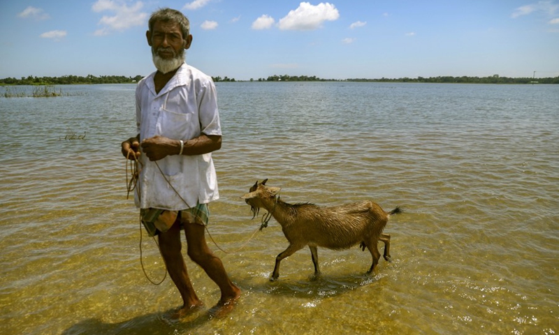 A man with a goat wades through a flooded road in Sunamganj, Bangladesh, on July 3, 2022.(Photo: Xinhua)