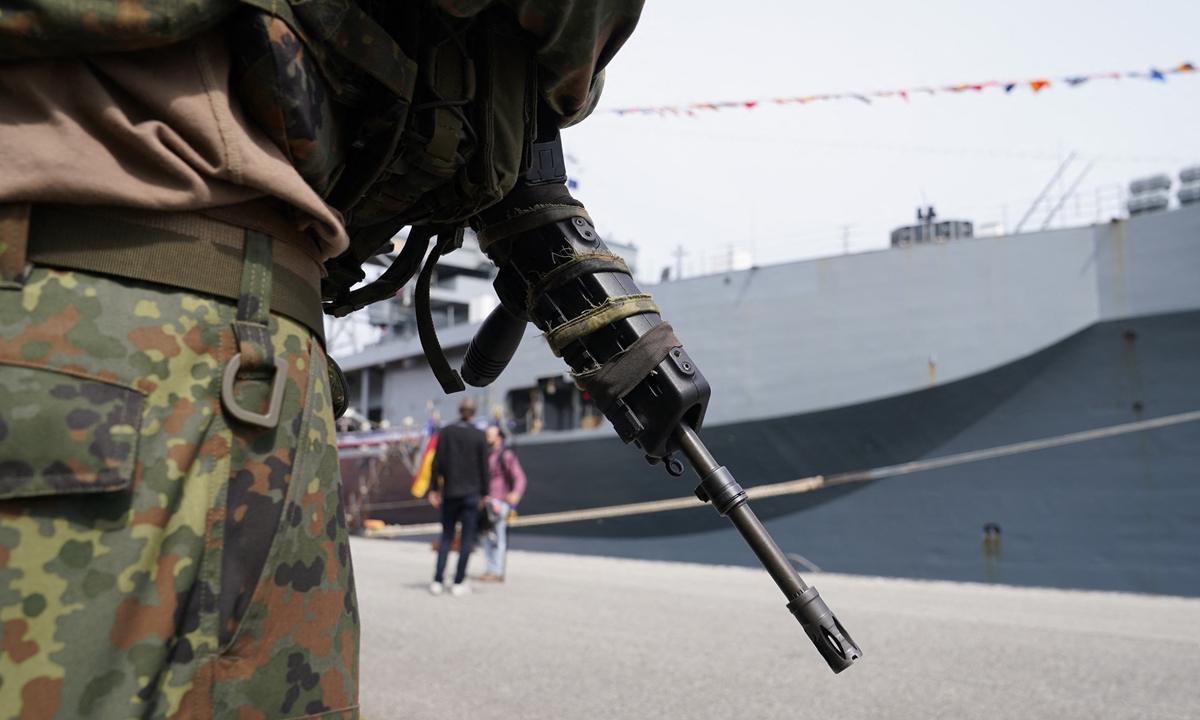 A soldier stands in front of the US ship 