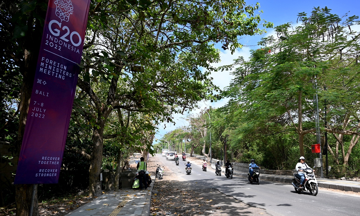 Motorcyclists ride past a banner for the G20 Foreign Ministerial Meeting scheduled to be held on July 7-8, outside the meeting venue in Bali, Indonesia on July 5, 2022. Guided by the theme 