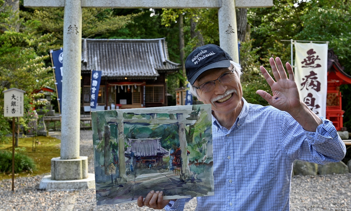Japanese art instructor Harumichi Shibasaki poses with a finished watercolor painting. Photos: AFP Japanese art instructor Harumichi Shibasaki paints with watercolors at 
a shrine. 