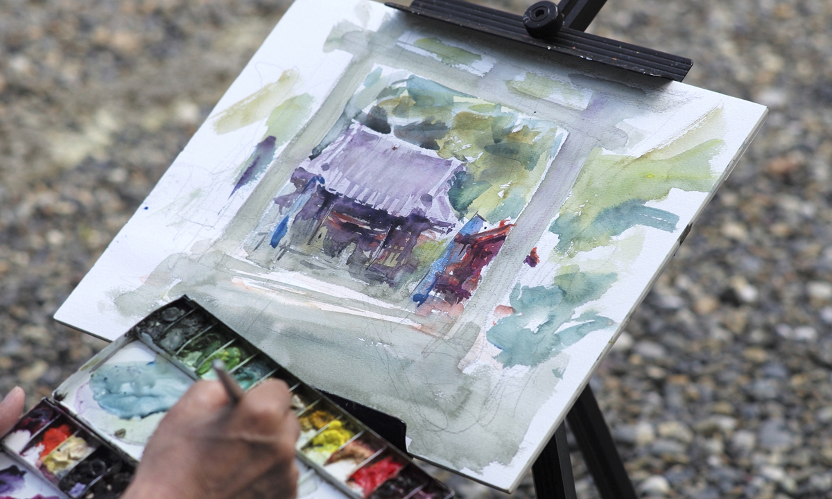 Japanese art instructor Harumichi Shibasaki poses with a finished watercolor painting. Photos: AFP Japanese art instructor Harumichi Shibasaki paints with watercolors at 
a shrine. 