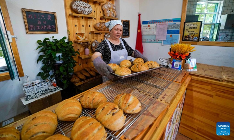 Elnur Esamidin, an employee of the Liuba Bakery, arranges bread on the shelf at the bakery in Yining City, northwest China's Xinjiang Uygur Autonomous Region, June 23, 2022. Located at a commercial area of Liuxing Street in Yining City, Liuba Bakery is well known for its quality bread. Besides, it has provided job opportunities for local women to increase their income.(Photo: Xinhua)