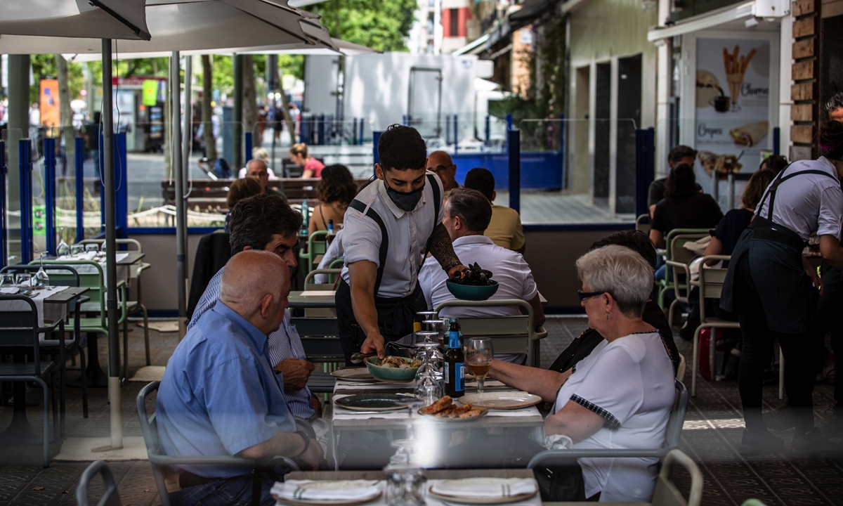 A waiter serves customers on a restaurant terrace in Barcelona, Spain, on June 5, 2021. Photo: VCG