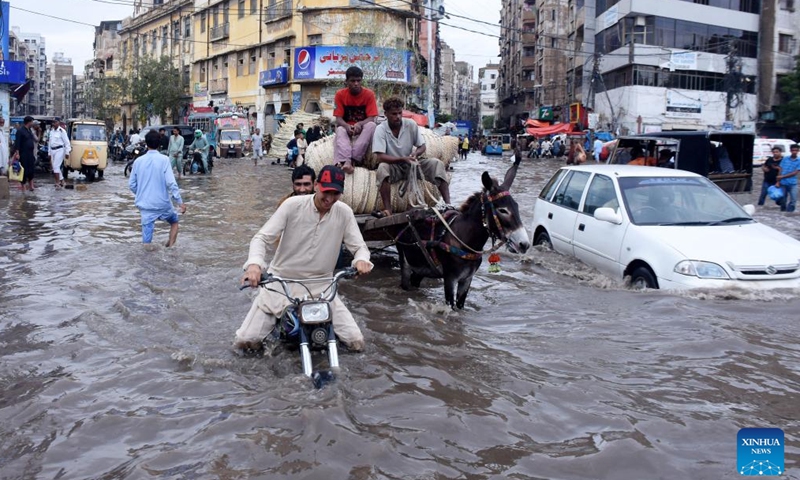 People and vehicles move on a flooded road after heavy rains in southern Pakistani port city of Karachi on July 9, 2022.Photo:Xinhua