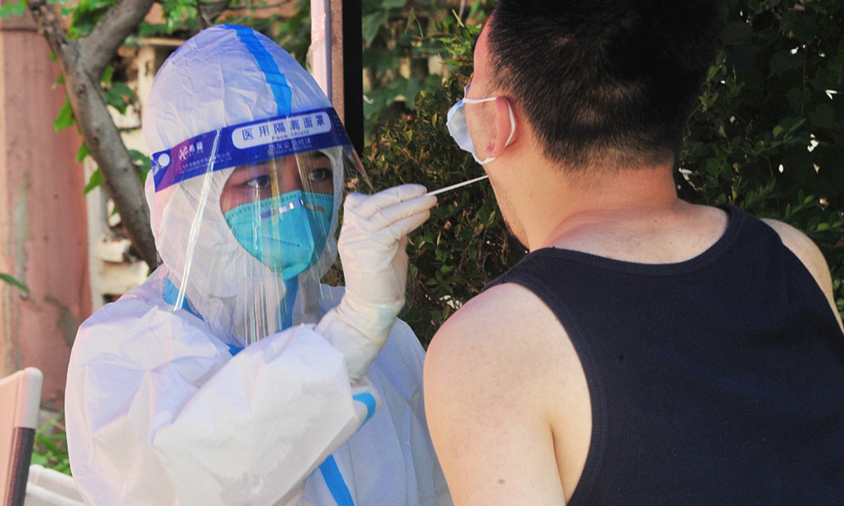 A medical worker takes a swab sample from a resident for nucleic acid test at a COVID-19 testing site in East China's Shanghai, July 9, 2022.