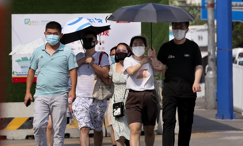 People walk on the street amid high temperature in Minhang District of east China's Shanghai, July 10, 2022.Photo:Xinhua