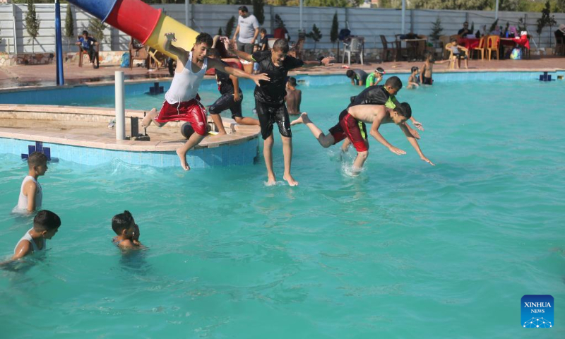 People cool themselves off in a pool during a hot day in the southern Gaza Strip city of Rafah, on July 16, 2022. (Photo by Khaled Omar/Xinhua)