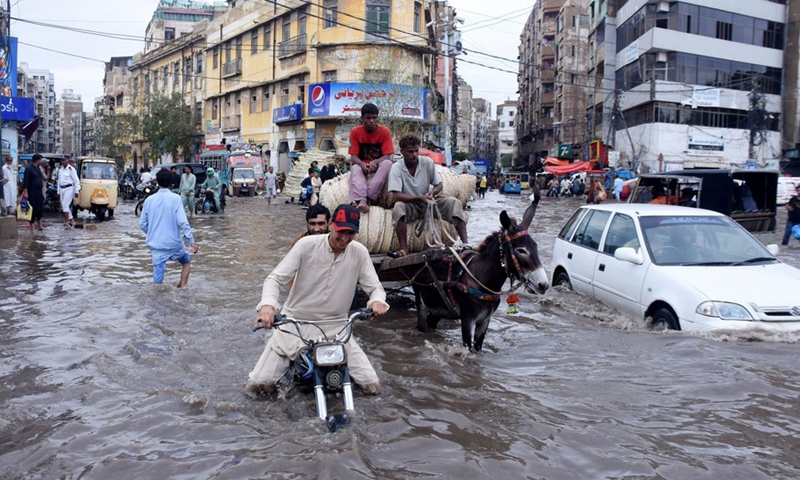 People and vehicles move on a flooded road after heavy rain in southern Pakistani port city of Karachi on July 9, 2022.Photo:Xinhua