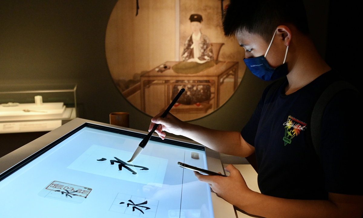 A man practices calligraphy on a screen at HKPM on July 3, 2022. 
Right: Standing Bodhidharma from the Dehua Kiln 
Top: HKPM Photos: IC