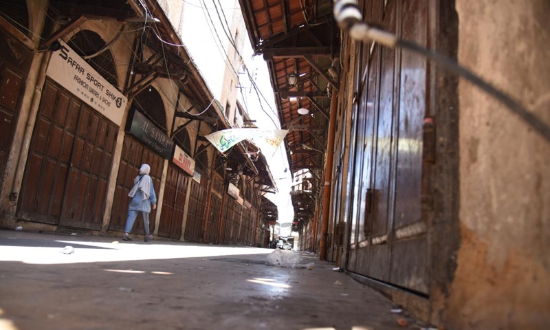 A woman walks past closed stores during the Eid al-Adha holiday in Tripoli, Lebanon, on July 10, 2022.Photo:Xinhua