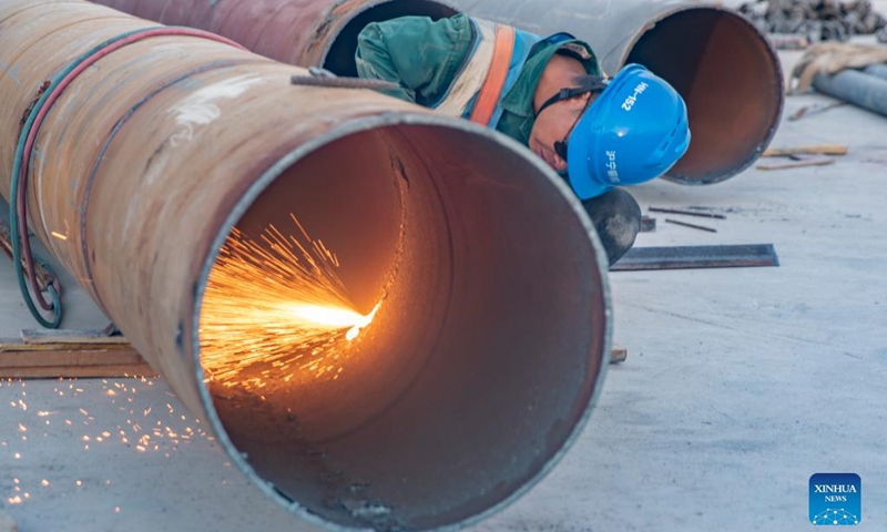A worker cuts a steel part at the construction site of the T3B terminal project of Chongqing Jiangbei International Airport in southwest China's Chongqing, July 11, 2022. Builders take shifts working for the construction of the T3B terminal project of Chongqing Jiangbei International Airport with preventing heatstroke measures in place.(Photo: Xinhua)