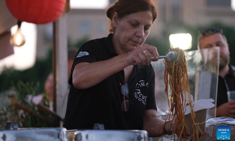 An employee fills a box with noodles at the Malta International Food Festival in Valletta, Malta, on July 13, 2022.(Photo: Xinhua)