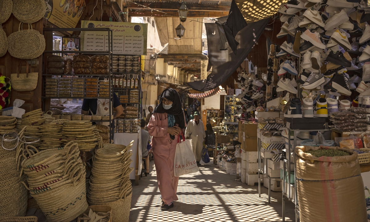 A woman walks past shops in the ancient Moroccan city of Fez, Morocco on June 8, 2022. Photos: AFP