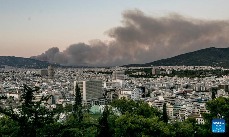 Photo taken on July 19, 2022 shows smoke caused by a massive wildfire rising from a mountain in the northern suburbs of Athens, Greece. A massive wildfire broke out Tuesday in the northern suburbs of Athens, damaging homes and forcing evacuations of local communities.(Photo: Xinhua)