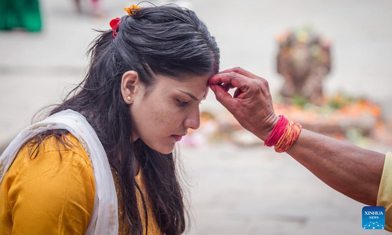 A devotee receives tika on her forehead after worshipping Lord Shiva during the first Monday of the holy month of Shrawan in Lalitpur, Nepal, July 18, 2022. The holy month of Shrawan is considered auspicious by Hindus for praying to Lord Shiva for happiness and prosperity.(Photo: Xinhua)