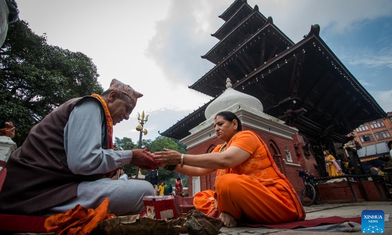 A devotee presents offerings to a priest during the first Monday of the holy month of Shrawan in Lalitpur, Nepal, July 18, 2022. The holy month of Shrawan is considered auspicious by Hindus for praying to Lord Shiva for happiness and prosperity.(Photo: Xinhua)